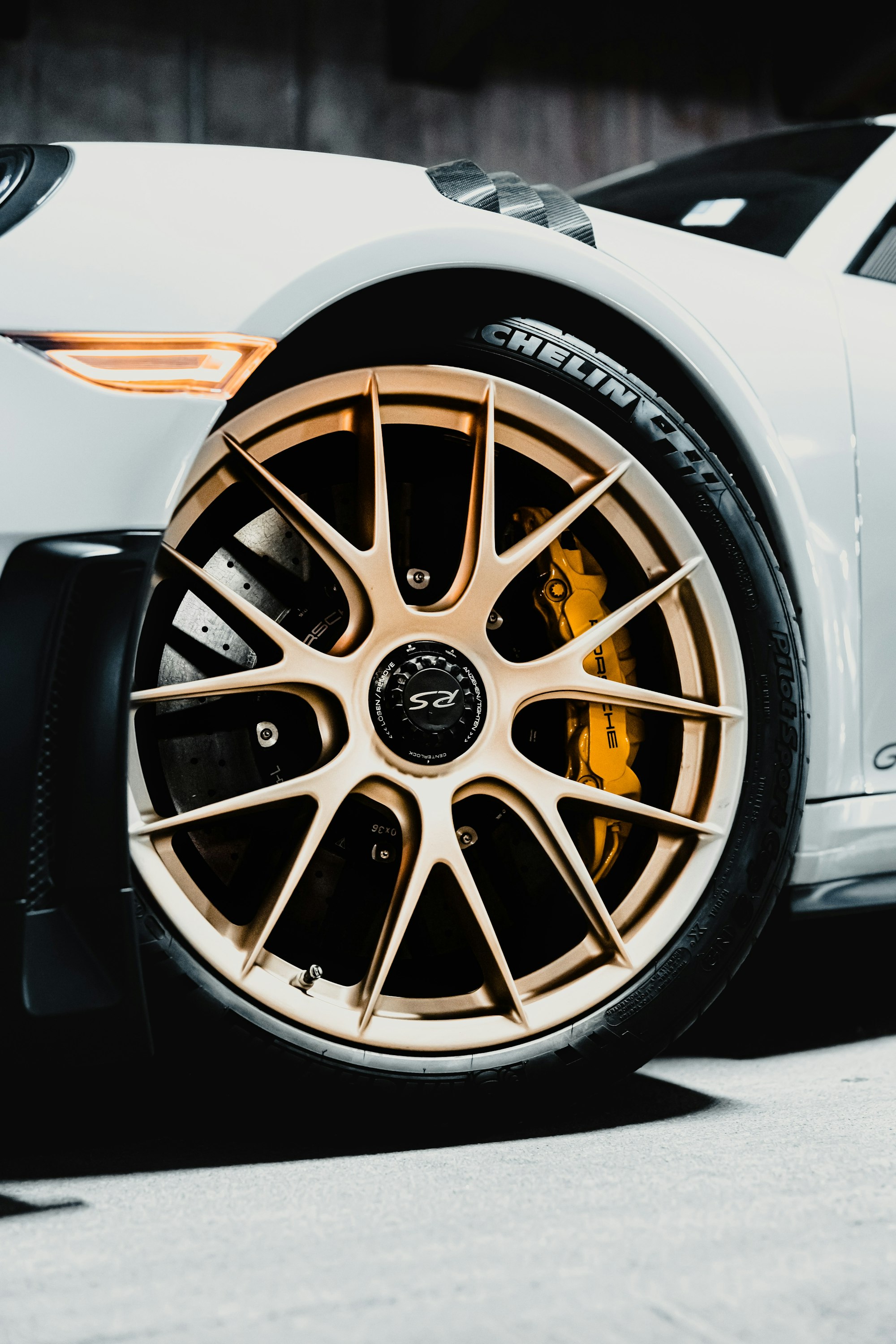 Close-up of a Porsche 911 GT3 RS front wheel with gold spokes, yellow ceramic brake calipers, and Michelin tire